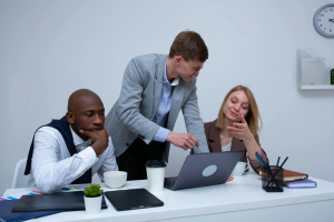 Diverse business team collaborating in modern office around laptop