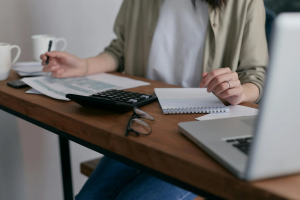 Woman working on finances at desk with laptop, calculator, and paperwork